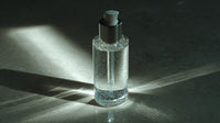 Clear bottle with a dark cap on a textured surface with light casting shadows